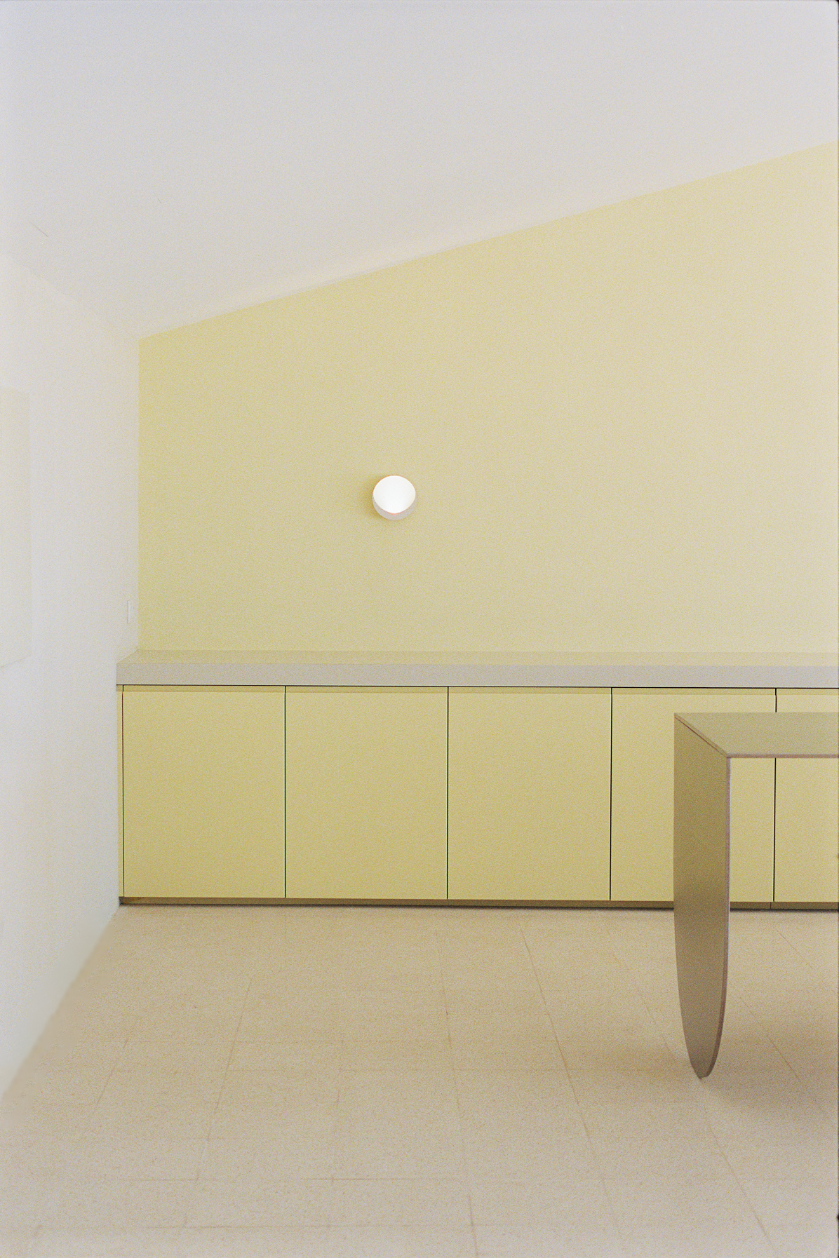 Pale yellow cabinetry and sconce